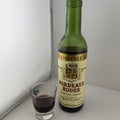 A half bottle of Cordier Bordeaux Rouge wine next to a small glass filled with dark red liquid.