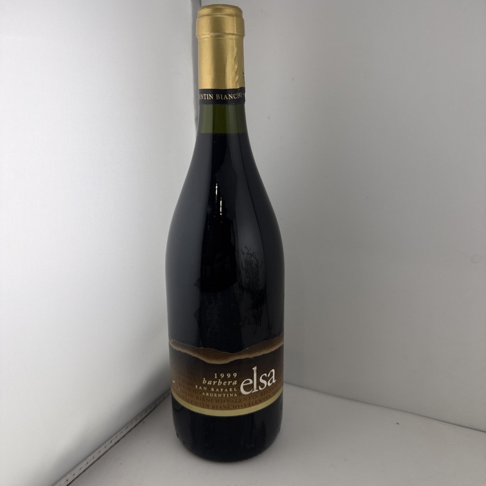 A bottle of 1999 Elsa Barbera red wine from San Rafael, Argentina, with a gold foil capsule.